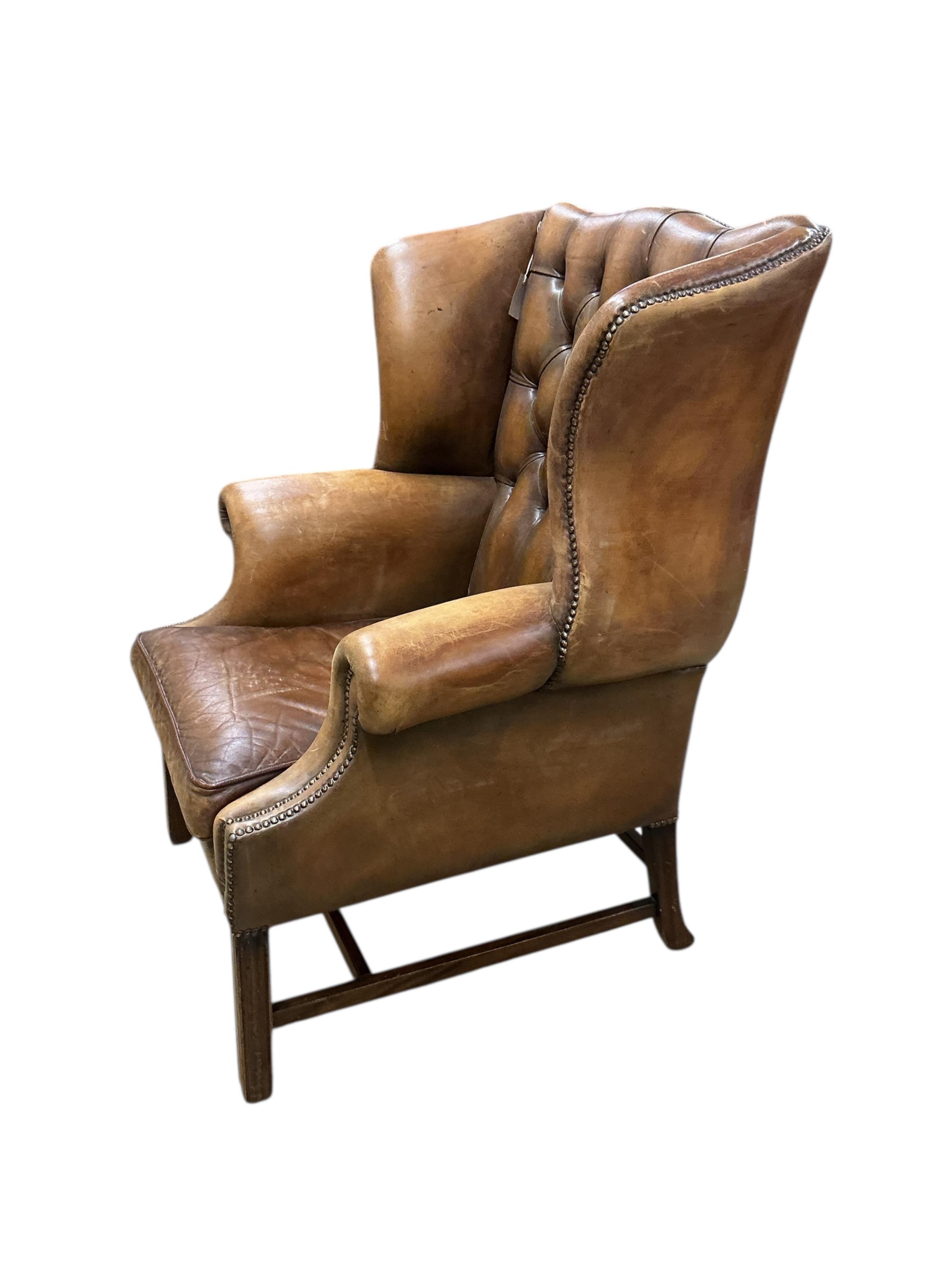 A reproduction George III style buttoned tan leather wing armchair, width 84cm, depth 74cm, height 110cm